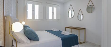 A neatly arranged bedroom with a bed, bedside lamp, and a bedside table.