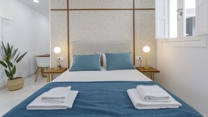 A neatly arranged hotel room with a large bed, two bedside tables with lamps, a desk, and a potted plant.