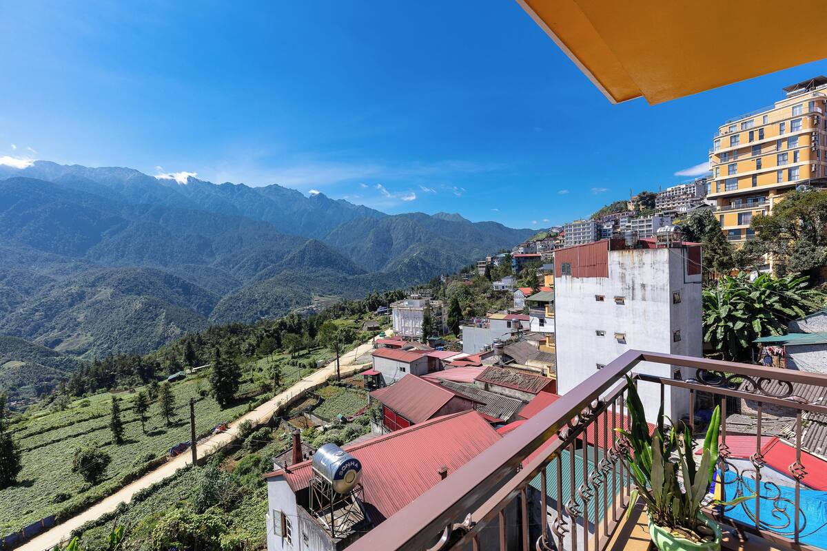 A mountainous landscape with buildings and a balcony with potted plants.