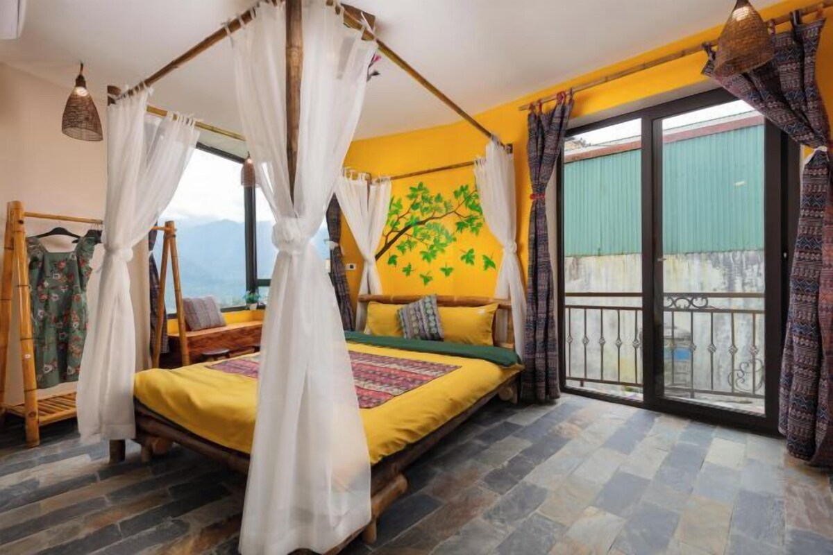 A bedroom with a bed, a canopy, a view of the outdoors, and a balcony.