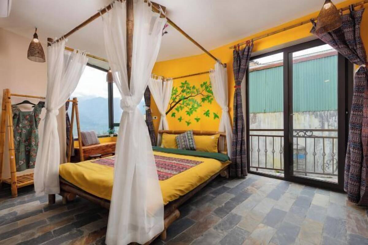 A bedroom with a bed, a canopy, a view of the outdoors, and a balcony.