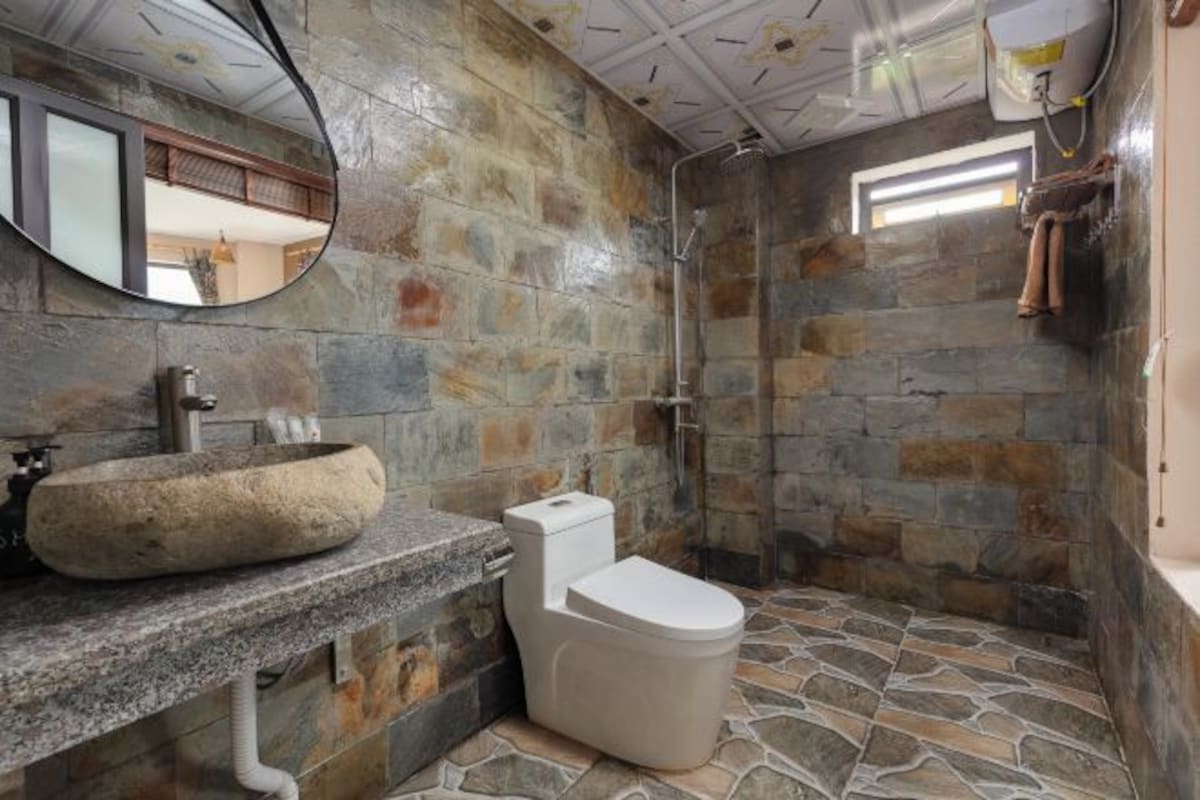 A bathroom with stone walls, a stone sink, and a toilet.