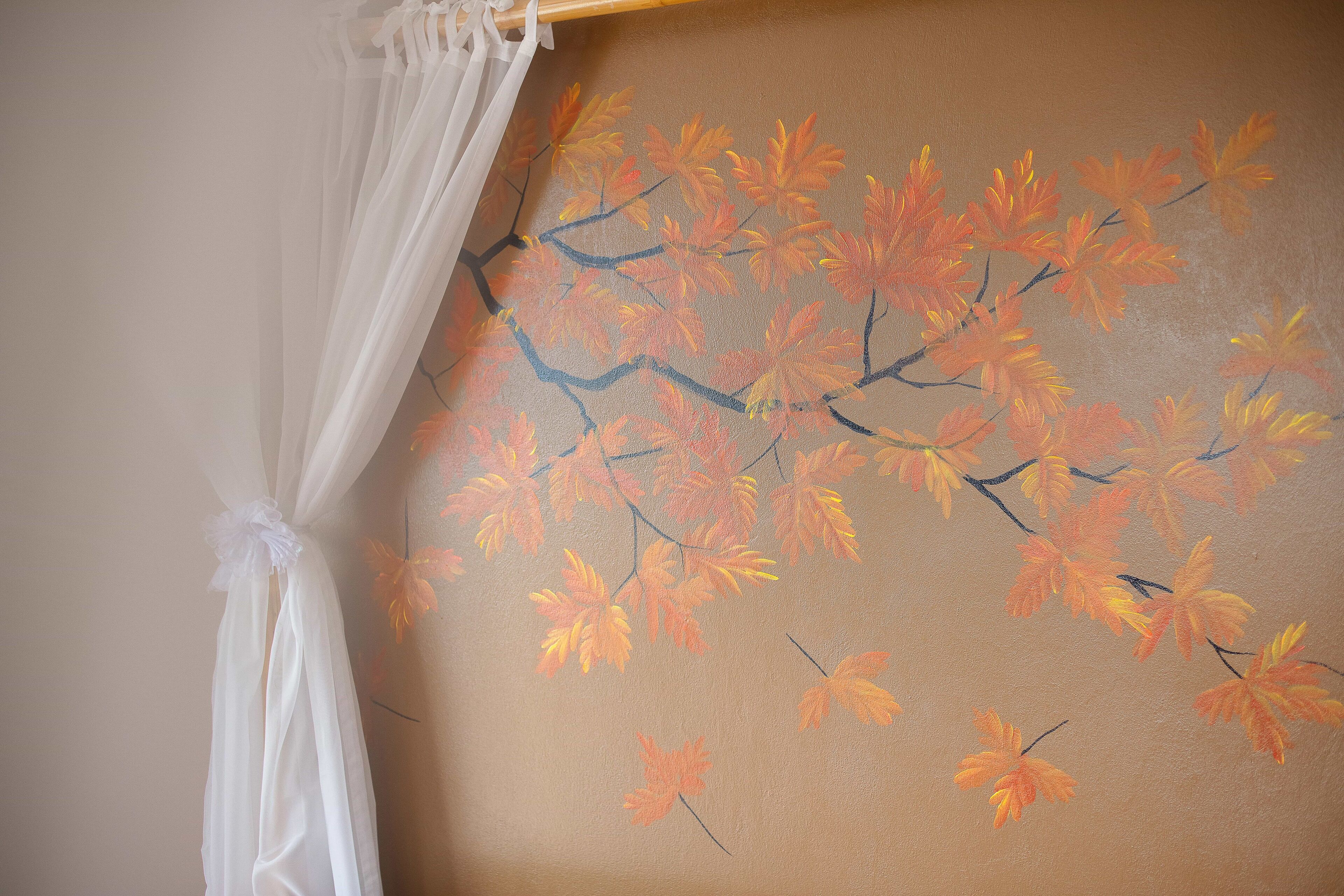 A wall with a painting of autumn leaves.