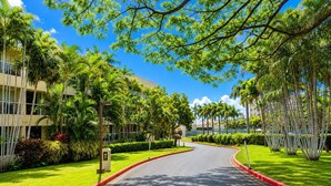 A curved driveway leading to a building with a 'T' sign, surrounded by lush greenery and palm trees. - Rare 3 Bedroom Penthouse at Maui Banyan | All En Suites and Heart of Kihei (Kihei)