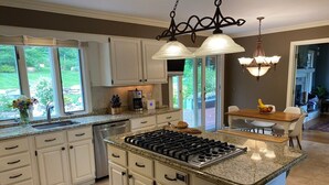 A kitchen with a central island, white cabinets, a gas stove, and a chandelier. - Hidden Oasis in the Mountains by Evergreen Home (Pittsfield)