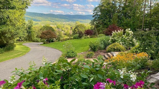 A winding driveway leading to a lush garden with various plants and flowers. - Hidden Oasis in the Mountains by Evergreen Home (Pittsfield)