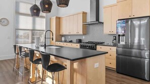 A modern kitchen with a central island, wooden cabinets, stainless steel appliances, and pendant lighting. - Red Fish Blue Fish🐟Private Pool Home👙Dogs OK🐶 (Okaloosa Island)