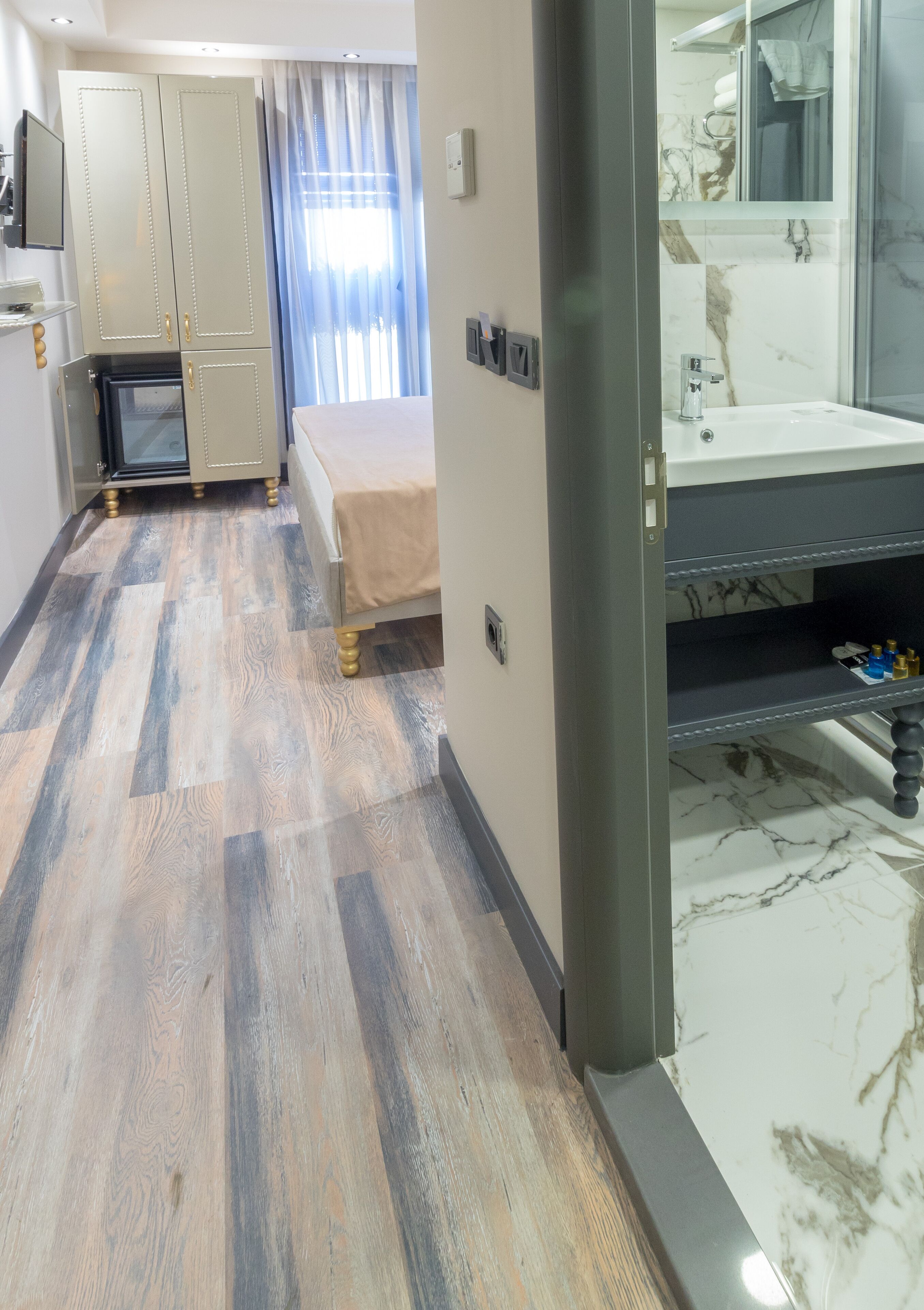 A hotel room with a bed, a vanity with a mirror, a sink, and a wardrobe.