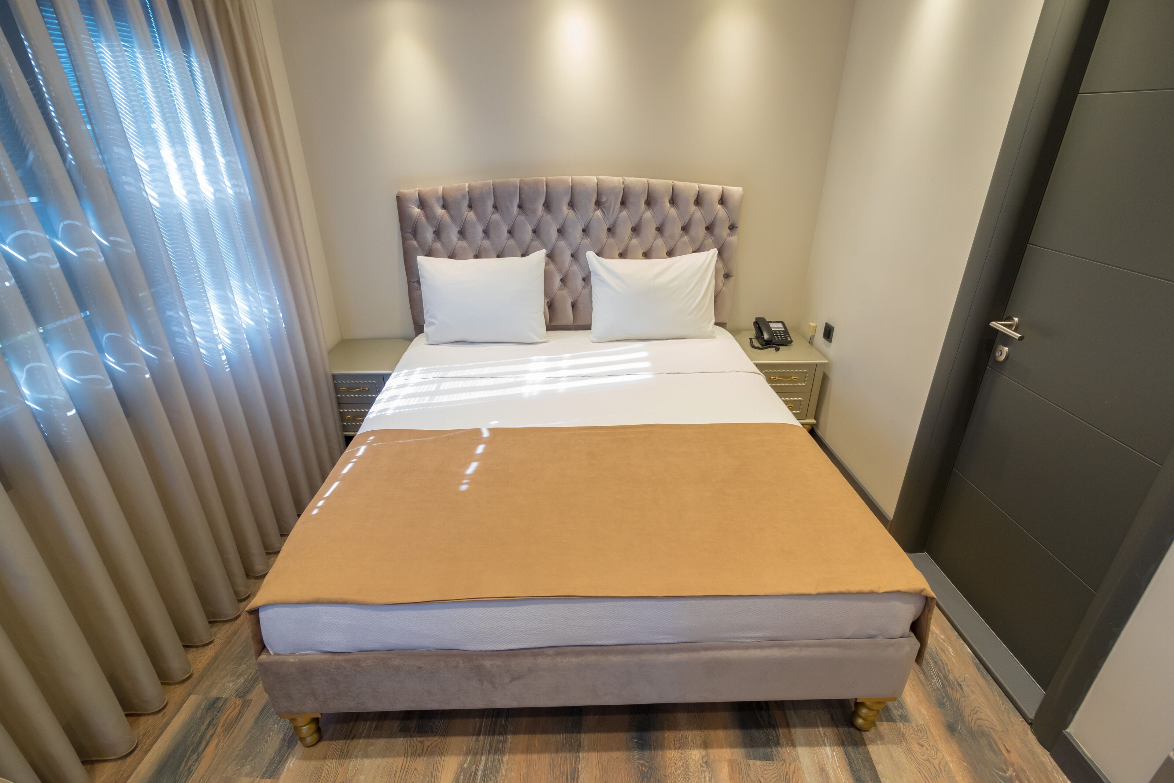 A neatly made bed with a brown blanket, a tufted headboard, and white pillows.
