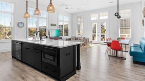 A modern kitchen with a large island, pendant lights, and a dining area with red chairs. - 1 Fish 2 Fish🐟Private Pool Home👙Dogs OK🐶 (Okaloosa Island)