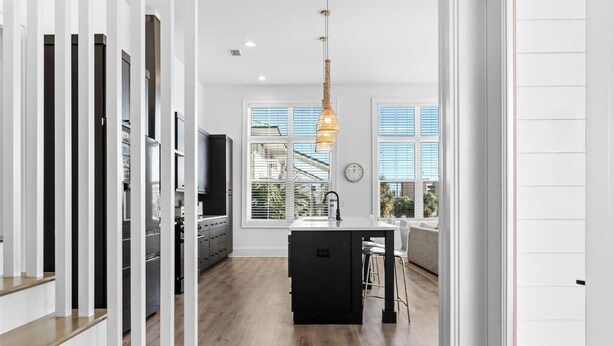 A modern kitchen with a central island, a dining area with stools, and a staircase leading to an upper level. - 1 Fish 2 Fish🐟Private Pool Home👙Dogs OK🐶 (Okaloosa Island)