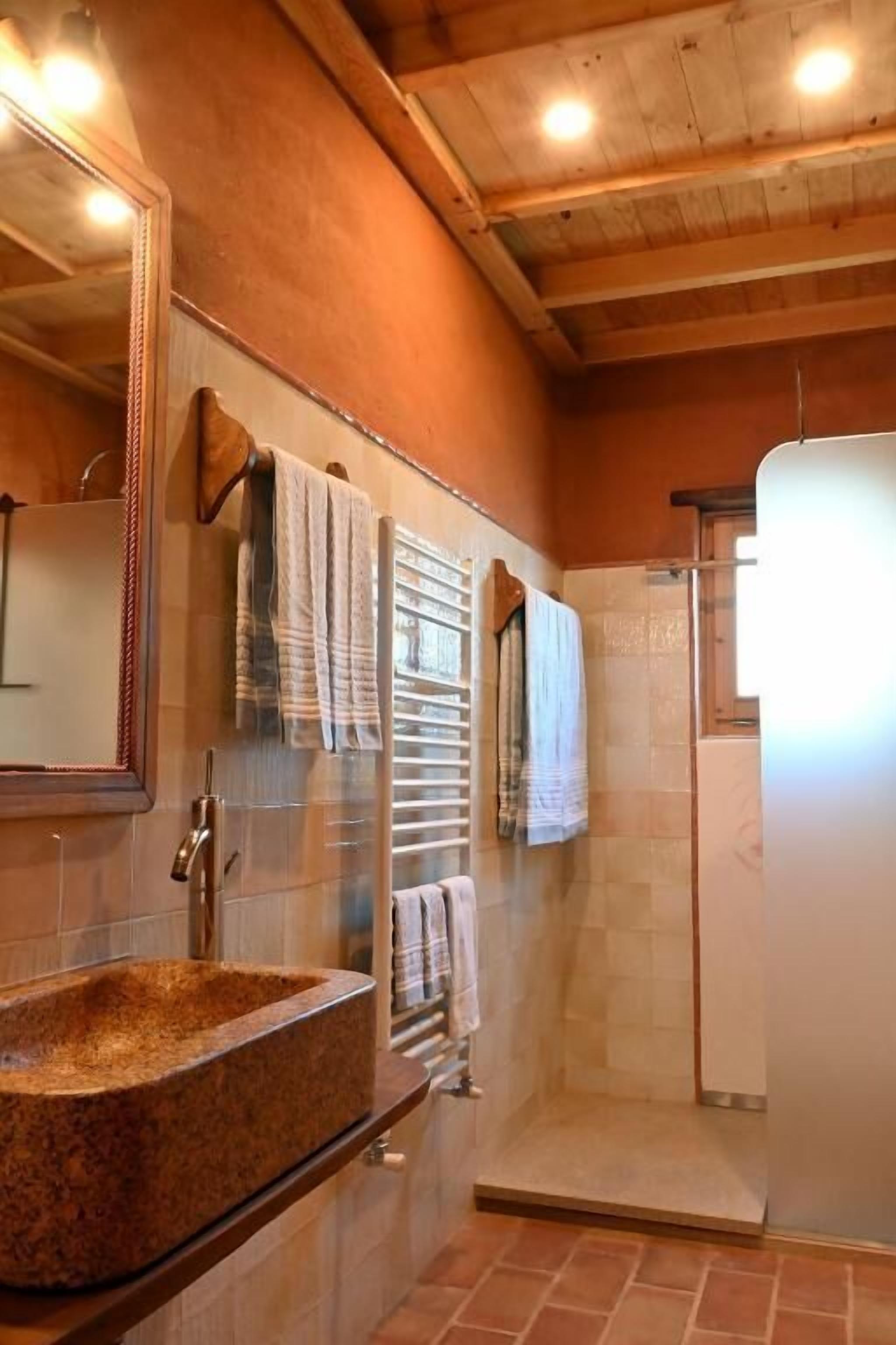 A bathroom with a granite sink, a mirror, a towel rack, and a shower area.