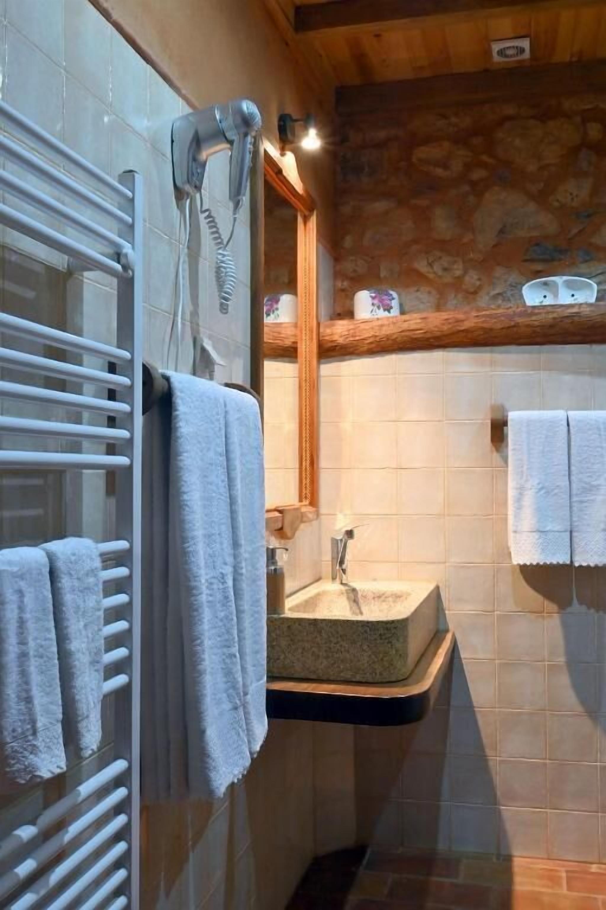 Un baño con toallero, secador de pelo, lavamanos y espejo.