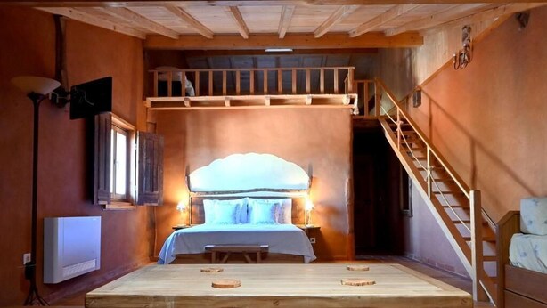 A cozy room with a bed, a wooden table, a bench, and a staircase. - Casal da Serra (Penha Garcia)