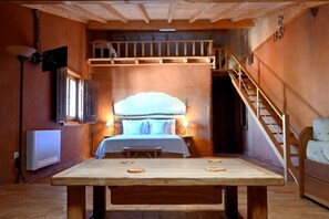 A cozy room with a bed, a wooden table, a bench, and a staircase. - Casal da Serra (Penha Garcia)