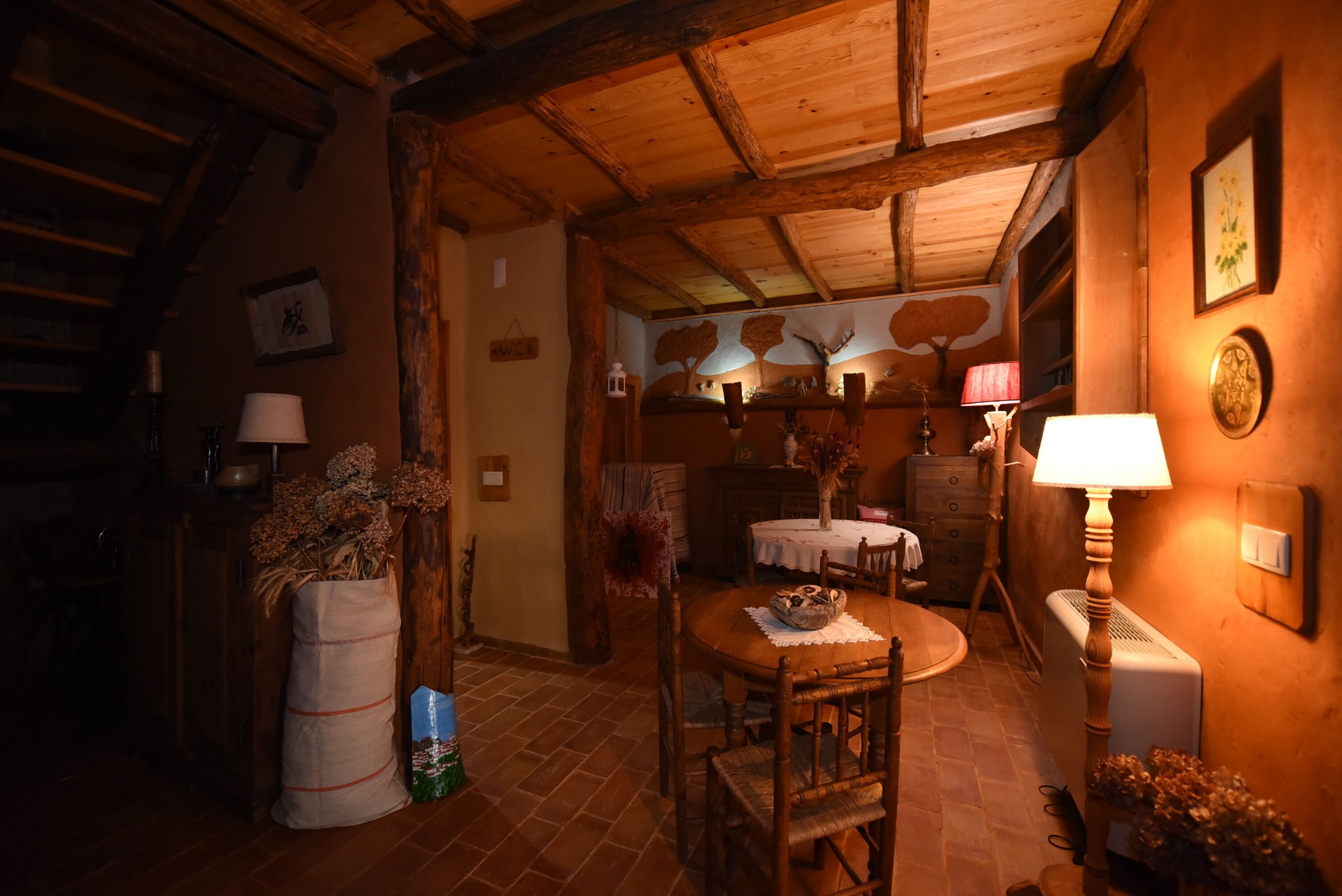 Un comedor acogedor con una mesa y sillas de madera, rodeado de decoración rústica y un ambiente cálido.