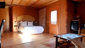 A wooden-floored bedroom with a bed, a table, and a television. - Casal da Serra (Penha Garcia)