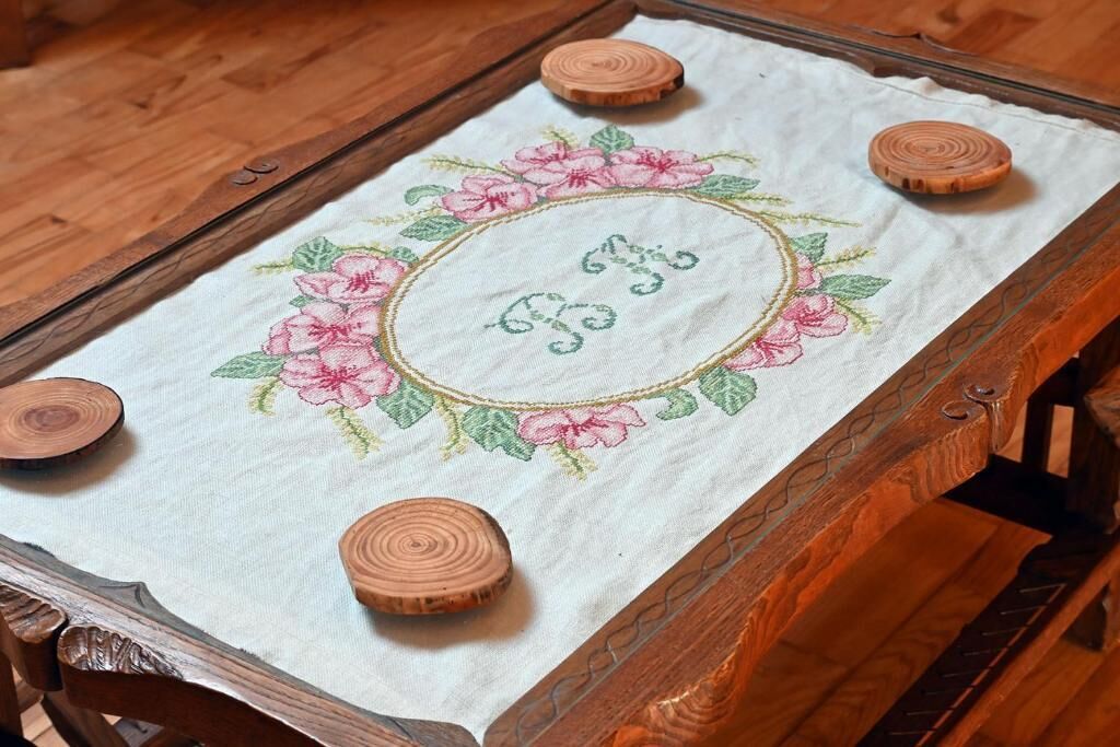 Ett träbord med ett vitt tyg som har broderade blommor och initialer.