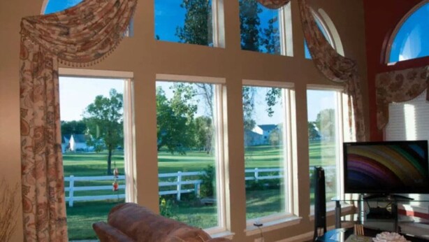 A room with large windows, a television, and a white fence visible outside. - Fairway Haven at The Falls – Golf, Shops, Dining! 10-12 Mins. Equestrian Center (O'Fallon)