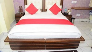 Ein Doppelbett mit Holzrahmen, zwei rote Kissen und eine weiße Bettdecke.