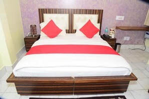 A double bed with a wooden frame, two red pillows, and a white bedspread.