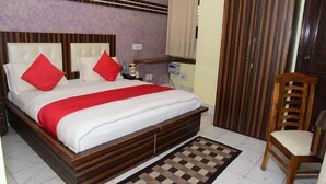 Ein Schlafzimmer mit einem hölzernen Bett, roten Kissen, einem karierten Teppich und einem Holzstuhl.