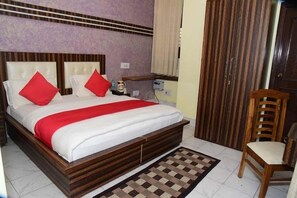 A bedroom with a wooden bed, red pillows, a checkered rug, and a wooden chair.