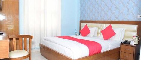 Un dormitorio ordenado con una cama, una mesita de noche de madera, una silla y un escritorio.