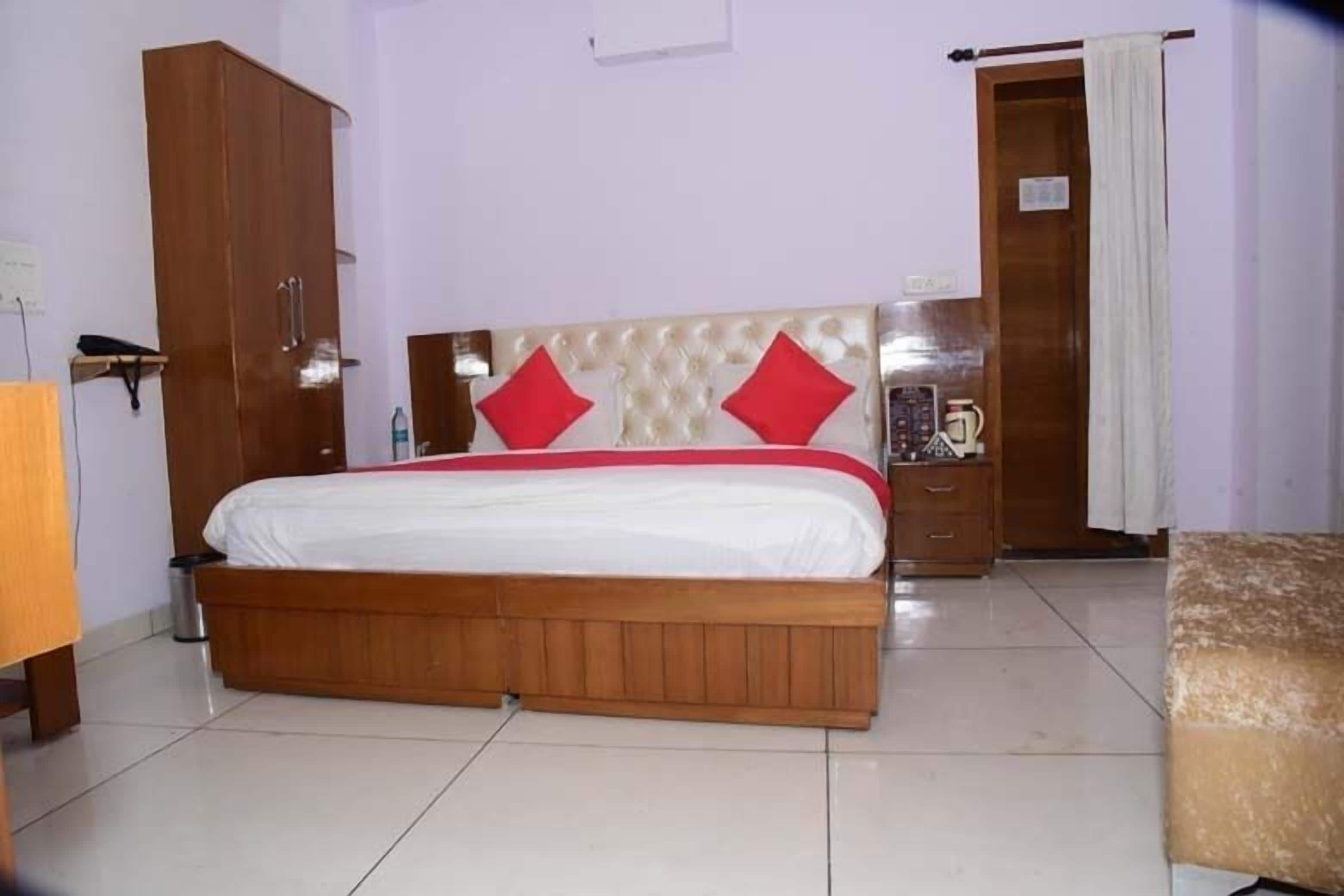 A bedroom with a wooden bed, a wardrobe, and a small table with a kettle.
