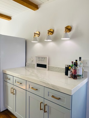 A kitchen with a marble countertop, gold handles, and wall-mounted lights.