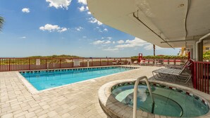 Una piscina al aire libre con hidromasaje, sillas de descanso y vistas a la playa.