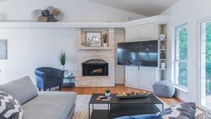 Un salon moderne doté d’une cheminée en pierre, d’un téléviseur à écran plat et d’un coin salon confortable.