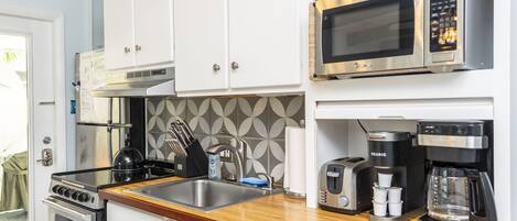 Una cocina moderna con armarios blancos, electrodomésticos de acero inoxidable, microondas, tostadora y cafetera.