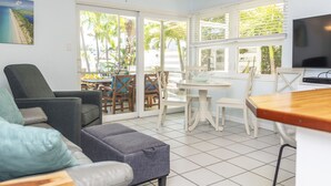 A living room with a sofa, ottoman, and a dining area with a table and chairs. - Razz's Retreat at KCB! (Key Colony Beach)