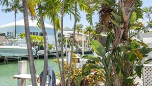 A marina with boats docked, palm trees, and a white building with a thatched roof. - Razz's Retreat at KCB! (Key Colony Beach)