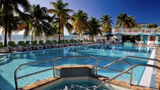 A swimming pool with a hot tub, surrounded by palm trees and lounge chairs. - Razz's Retreat at KCB! (Key Colony Beach)