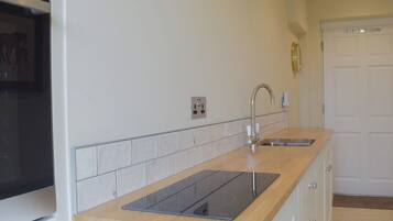 A kitchen with a wooden countertop, a built-in stove, a sink, and a white tiled backsplash.
