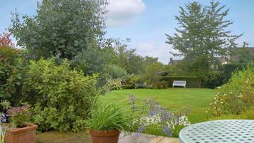 A garden with a lawn, potted plants, and a metal table.