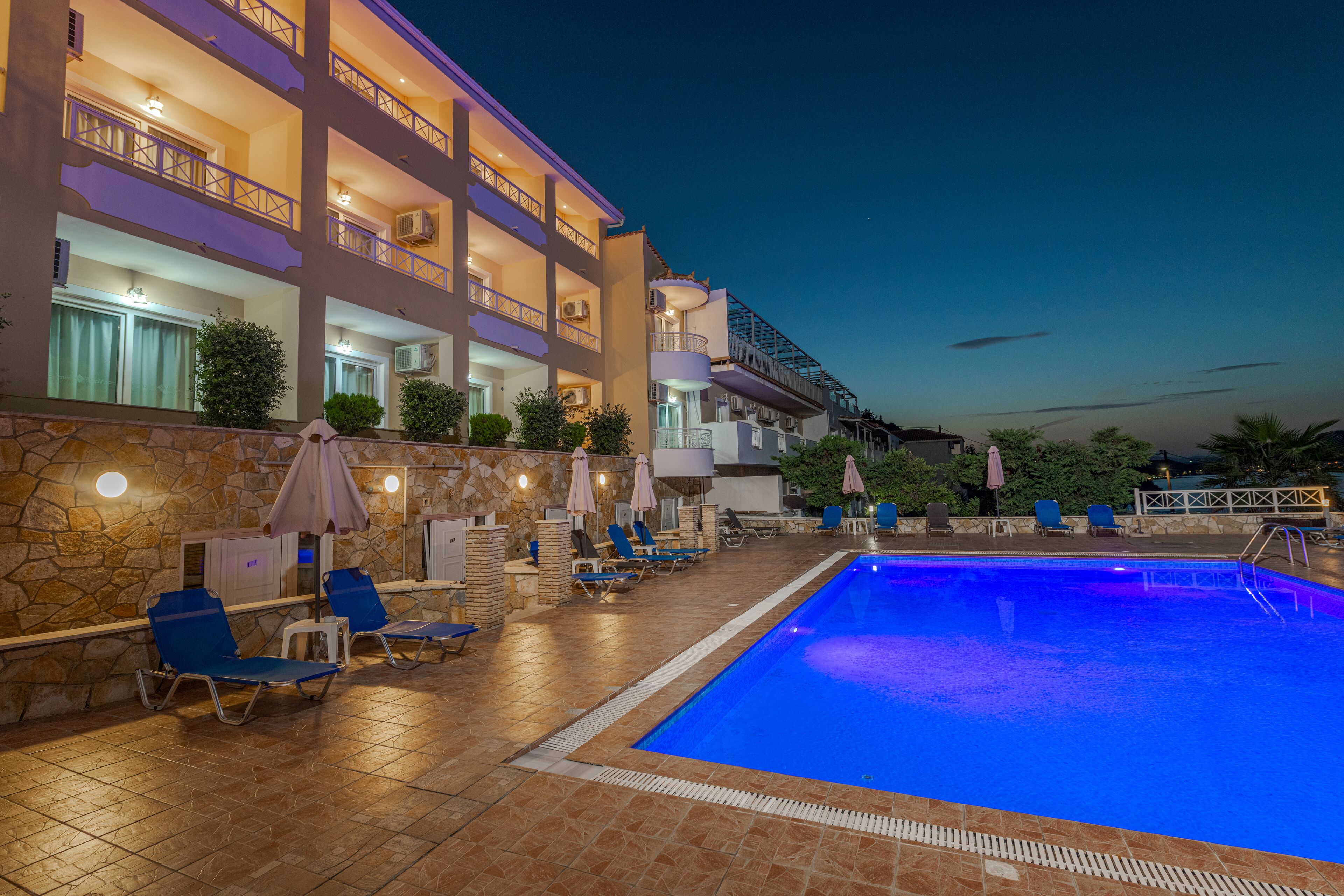Un hotel con piscina, sillas de descanso y sombrillas.