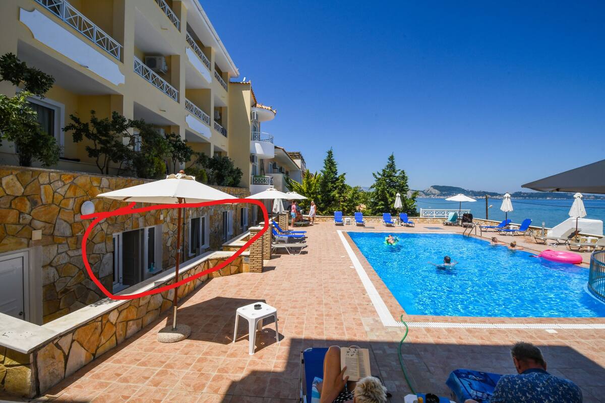 A pool area with lounge chairs, umbrellas, and a stone wall.