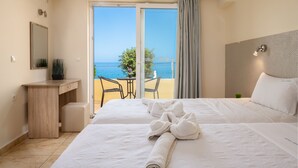 Quarto de hotel com uma cama, uma escrivaninha, uma cadeira e vista para o mar.