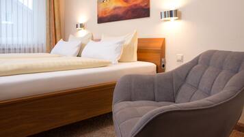 Una habitación de hotel con una cama, un sillón gris y un cuadro en la pared.