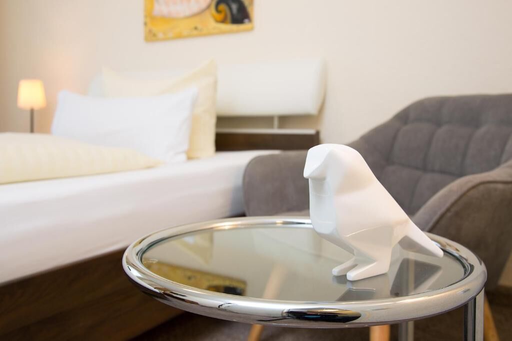 A bed with white bedding and a gray armchair in a hotel room.