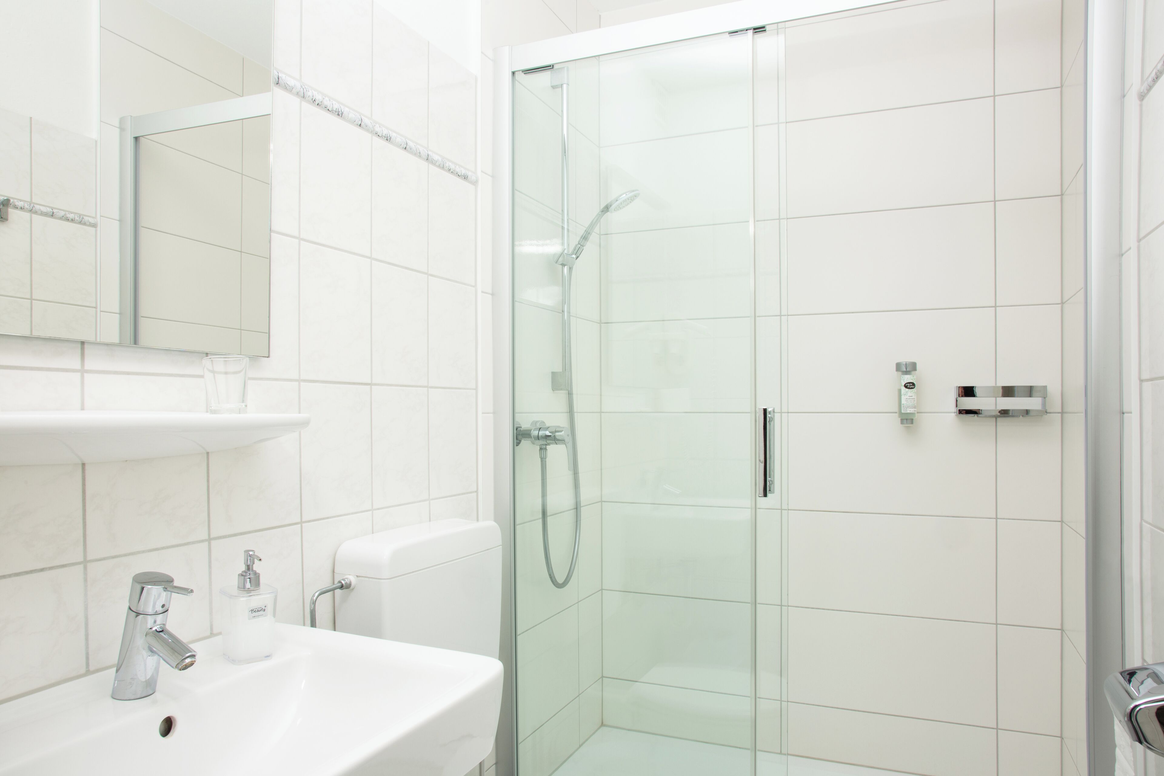 A modern bathroom with a glass-enclosed shower, a white sink, and a mirror above the sink.