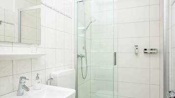 A modern bathroom with a glass-enclosed shower, a white sink, and a mirror above the sink.