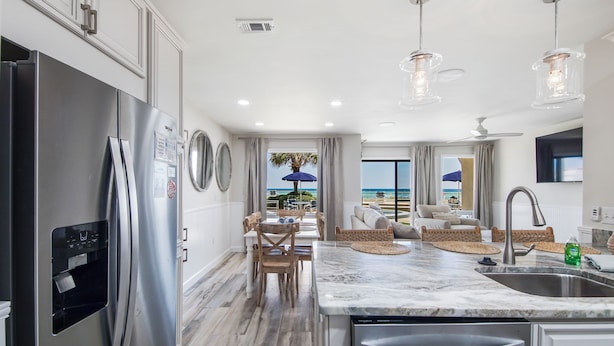 A modern kitchen with a marble countertop, stainless steel appliances, and a view of the ocean through large windows. - Latitude 14 - NEW OWNER! NEW LOOK! Spectacular ocean views! 1BD/2BA. Sleeps 6 (Panama City Beach)