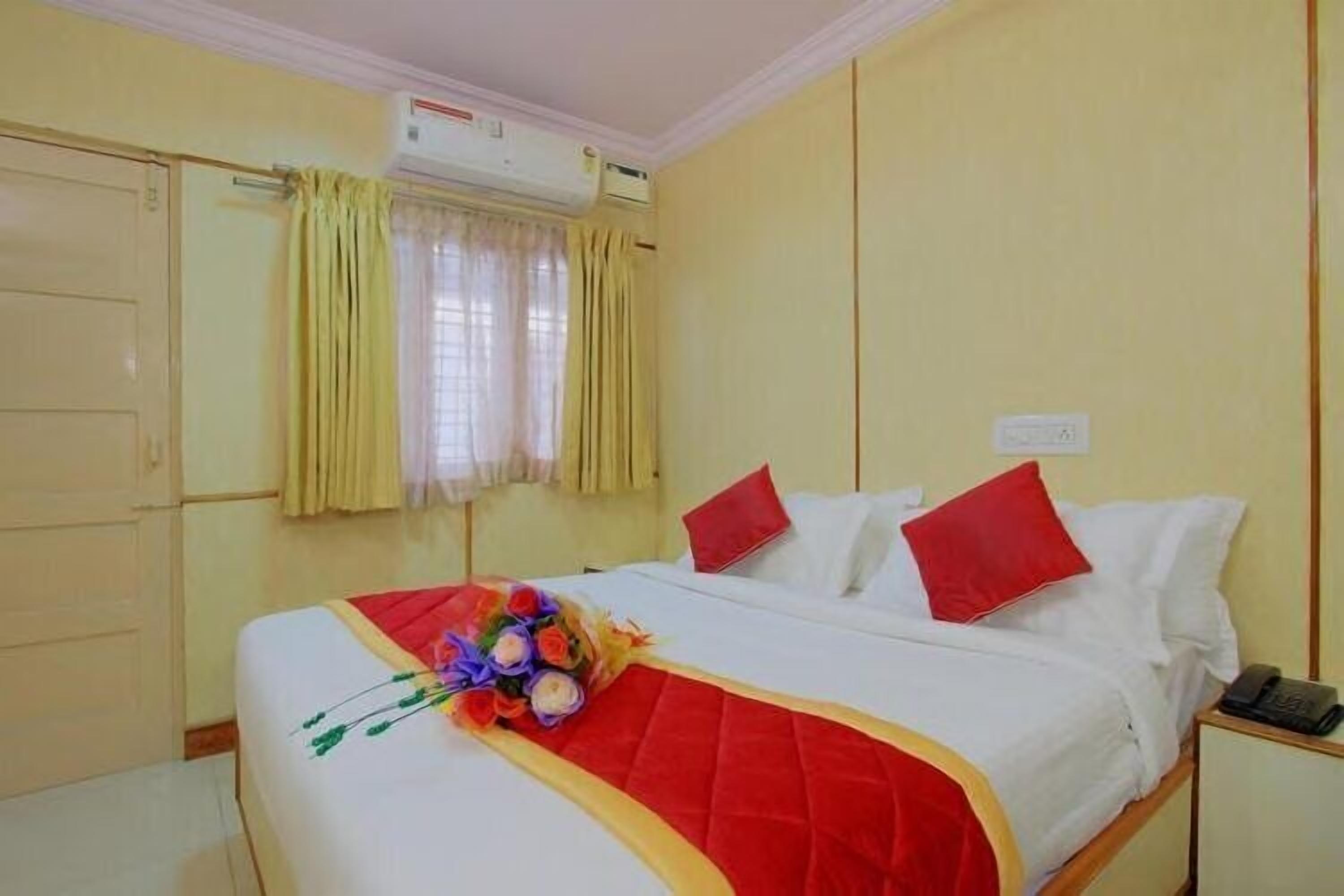 A hotel room with a bed, a bedside table, and a window with curtains.