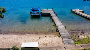 A clear view of a dock extending into a calm lake with a boat moored at the end.