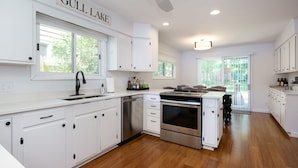 A modern kitchen with white cabinetry, stainless steel appliances, and a view of the outdoors.