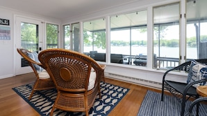 A sunroom with large windows, wicker chairs, and a view of the outdoors.